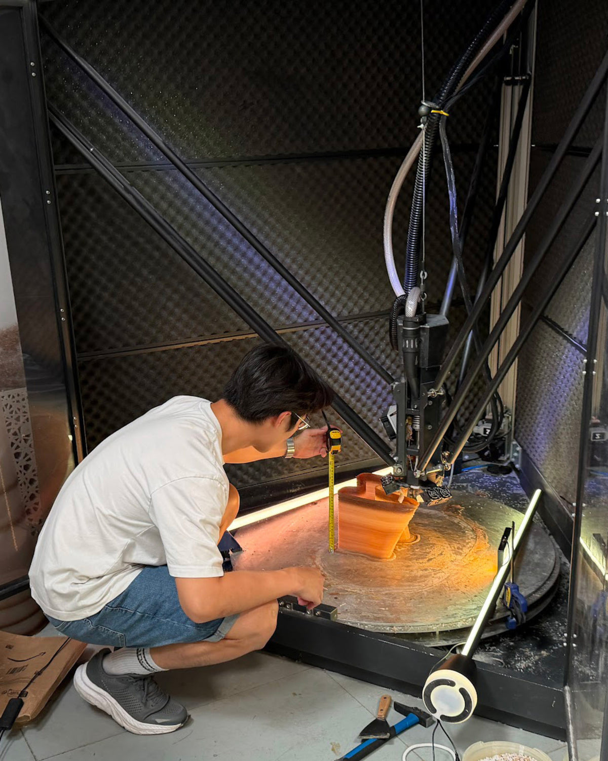 Designer Chao-Chun Kung measuring an orange 3D-printed prototype during fabrication testing at Fab.Pub.