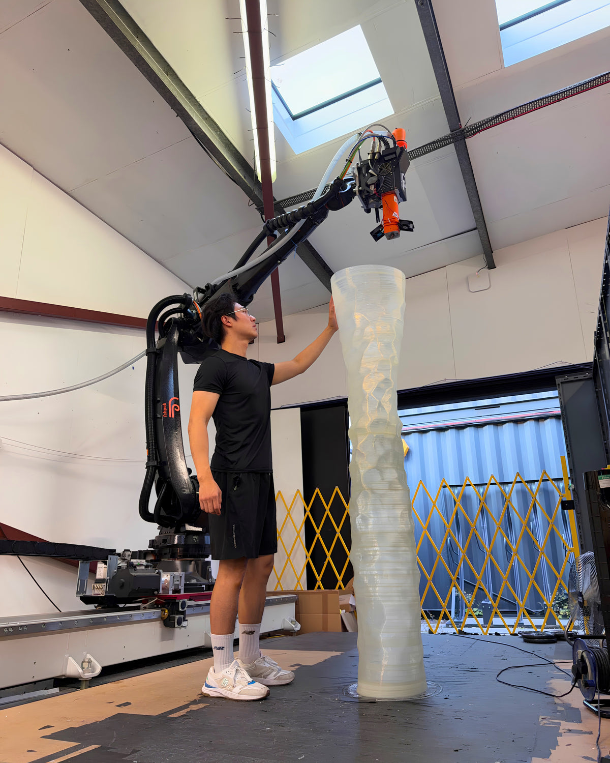 Designer Chao-Chun Kung inspecting a full-scale 3D-printed lighting prototype beside Fab.Pub’s KUKA robotic fabrication system.